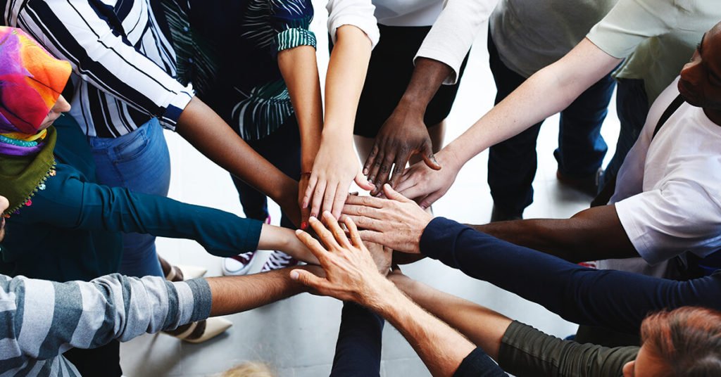 Culture in the workplace - multiple hands in for teamwork